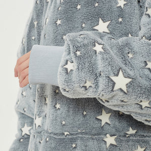Snuggyz star glow-in-the-dark hoodie blanket draped over a sofa, showing soft fabric and cozy design for warmth and comfort.