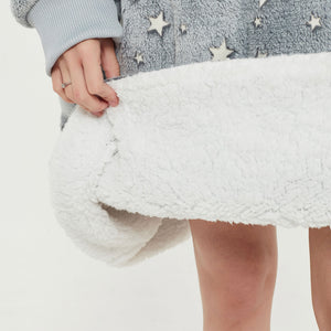 Snuggyz star glow-in-the-dark hoodie blanket draped over a sofa, showcasing its cozy, soft fabric with star patterns in low light.