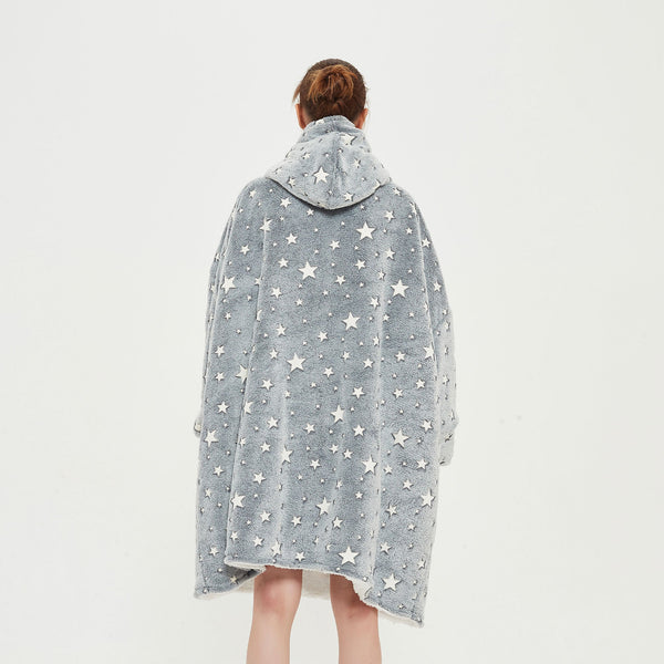 Snuggyz star glow-in-the-dark hoodie blanket draped over a sofa, showing soft fabric and star patterns in a cozy living room setting.